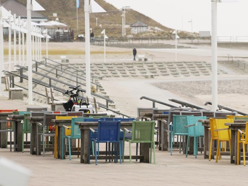 Einsame Tische und Stühle stehen auf der Strandpromenade.