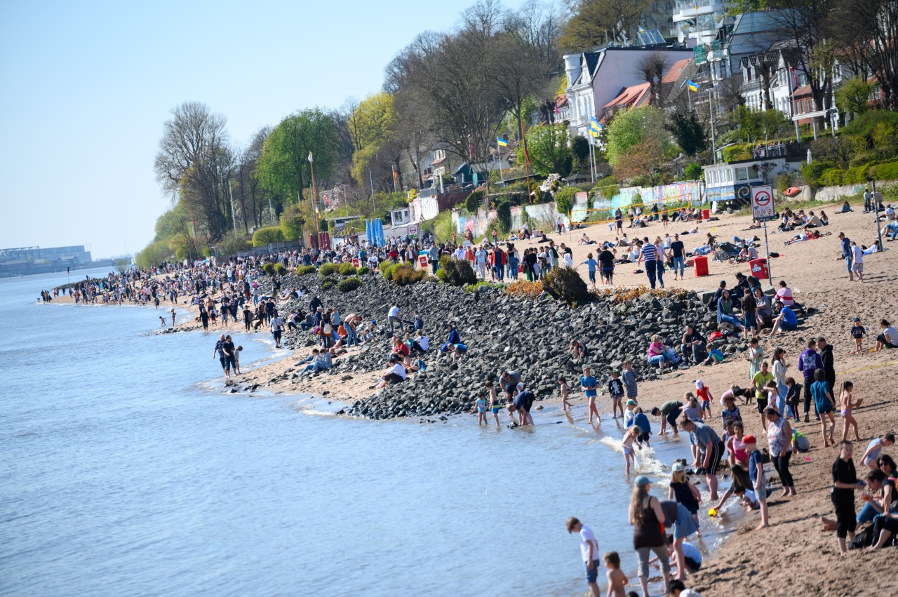 Zahlreiche Menschen sind bei Sonnenschein am Elbstrand in Hamburg unterwegs.