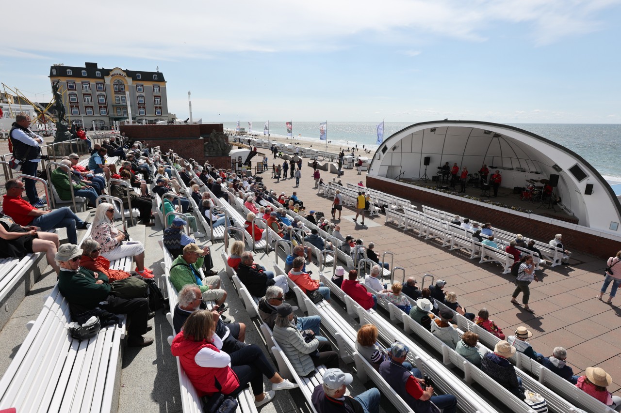 Besucher auf Sylt verfolgen an der Kurpromende an der "Musikmuschel" ein Konzert. 