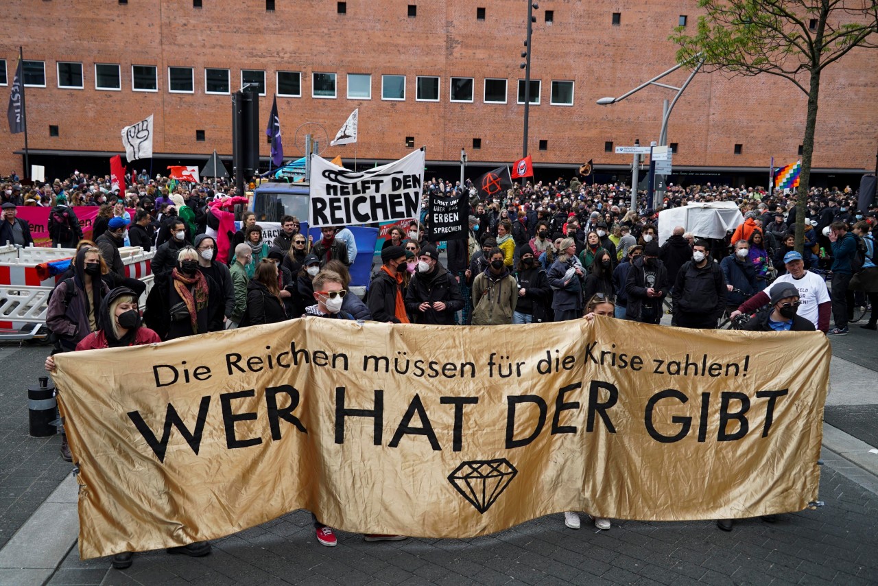 1. Mai: Mehrere hundert Teilnehmer demonstrieren friedlich in Hamburg. Vorne halten sie ein Plakat mit der Aufschrift „Wer hat, der gibt“.