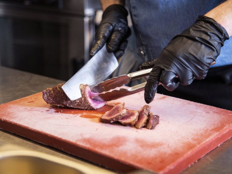 Ein Koch schneidet ein Steak in Scheiben.