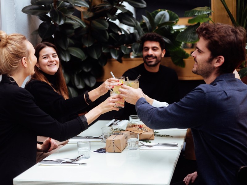 Freunde sitzen am Esstisch und stoßen an